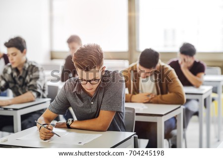 Group of high school students doing exam at classroom.