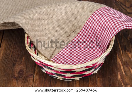Empty wooden fruit or bread basket on an old vintage planked wood table with burlap sack cloth