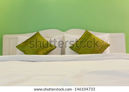 White bed with green pillows in green room