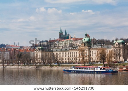 View of Prague Castle from across the Vitava river with a tourist boat, czech republic.