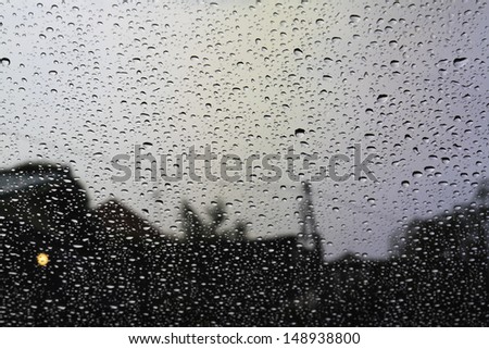 Raindrops on the glass of car and village as a background