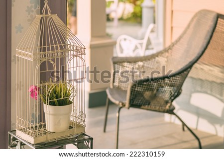 interior of vintage cage with flower vase and wicket chair in home