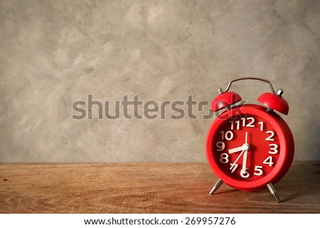red alarm clock on wood table in vintage color style