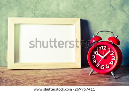 red alarm clock on wood table in vintage color style