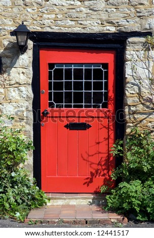 An old red door to the front of an English country cottage