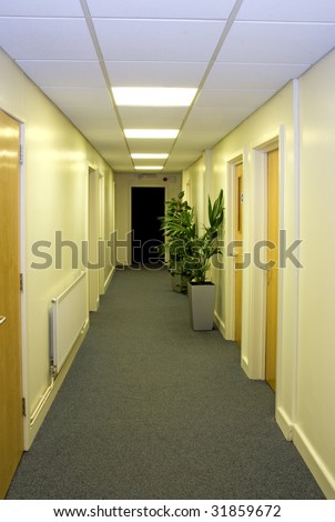 Long yellow office corridor with a dark room at the end.