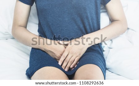 Beautiful Attractive Asian woman wearing white shirt sitting on bed have a bladder pain or uti pain after wake up in the morning feeling so illness,Healthcare Concept.