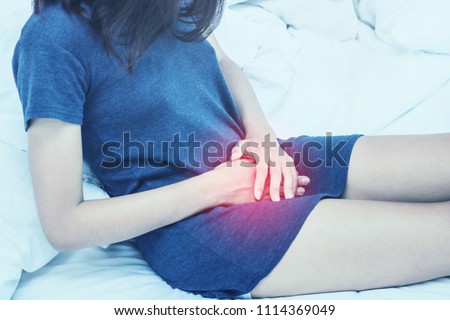 Beautiful Attractive Asian woman wearing white shirt sitting on bed have a bladder pain or uti pain after wake up in the morning feeling so illness,Healthcare Concept.color tone