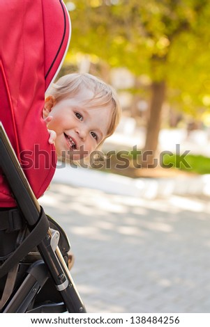happy baby in a stroller looks out laughing in the park happy baby in a stroller looks out laughing in the park