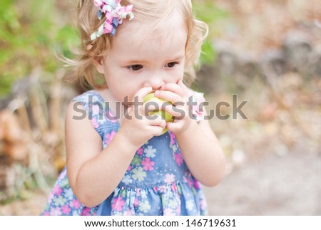 cute baby eats a green apple outdoors selective focus