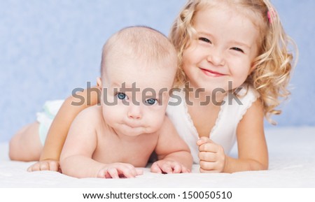 Happy Little Sister Hugging Her Brother Lying