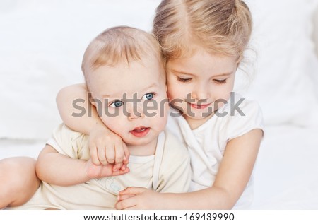 happy little sister hugging her brother on a white background
