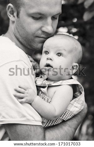 Father Holds Baby Son In Her Arms In The Open Air ( Black And White )