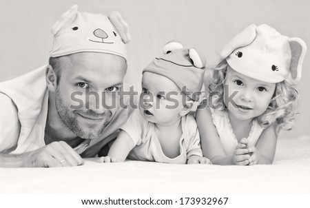 happy dad with kids in funny hats lying on the bed ( black and white )