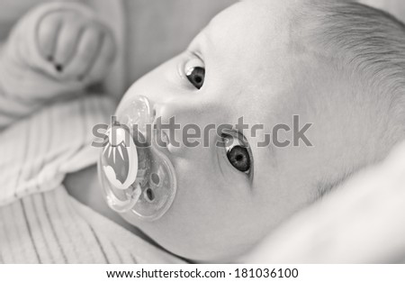 cute baby with pacifier lying in a cradle ( black and white )