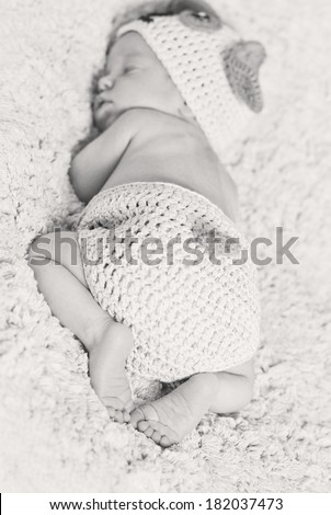cute newborn baby sleeps in a knitted hat dogs focus on legs ( black and white )