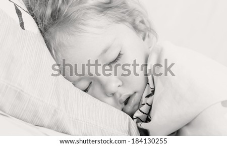 little girl is sleeping covered with a blanket ( black and white )