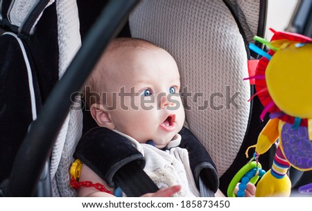 baby boy in car seat stares at the toy