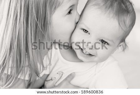 happy little girl hugging kissing his brother ( black and white )