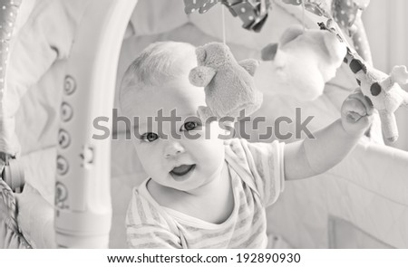 Baby boy playing sitting in the cradle with mobile toy giraffe ( black and white )