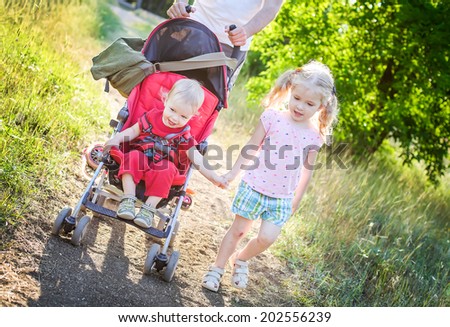 little sister holding the hand with her little sibling in  a stroller
