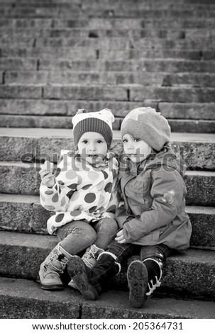 cheerful little girls friends sitting on the stairs ( black and white )
