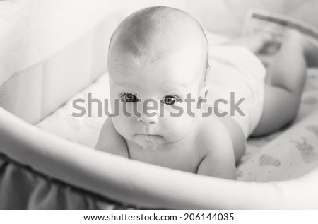 baby curious peeping out of the crib and looking at the camera ( black and white )