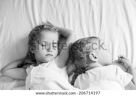 charming little brother and sister asleep  on white background ( black and white )