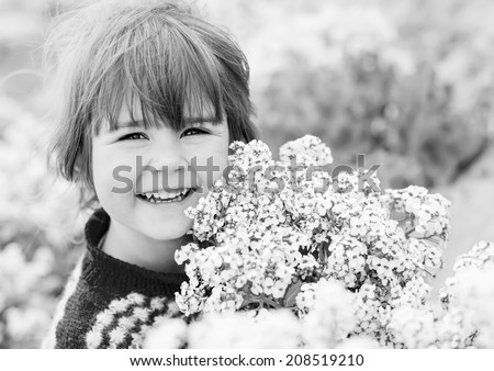 funny happy little girl holding a bouquet of standing on a meadow ( black and white )