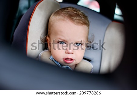 Portrait of a cute toddler boy sitting in the car seat