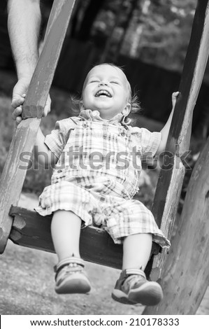 Laughing toddler boy ride on a swing (black and white )
