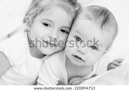 happy little sister hugging her brother on a white background ( focus on one child ) (black and white)
