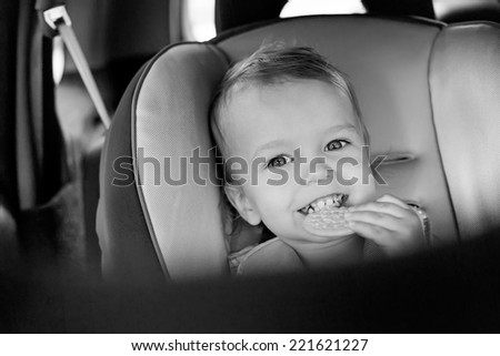 Happy Toddler boy in the car eating cookies ( black and white )