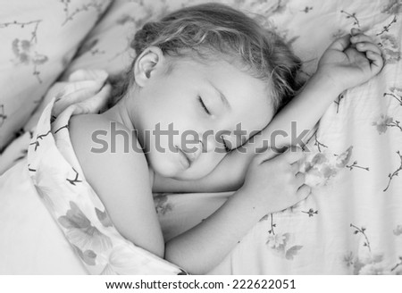 toddler girl is sleeping covered with a blanket  ( black and white )