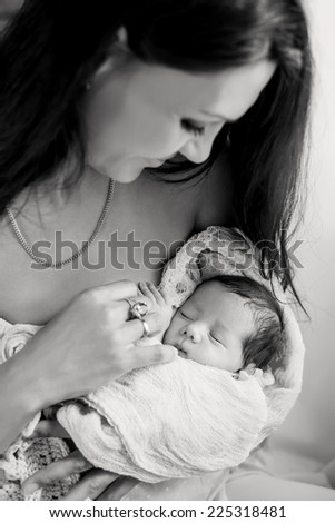 Happy attractive mother holding newborn baby on a white background ( black and white )