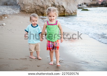 Small children brother and sister on the beach walk