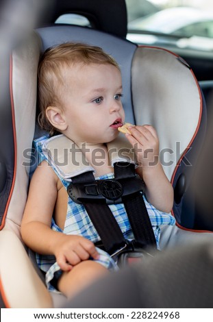 Happy Toddler boy in the car eating cookies