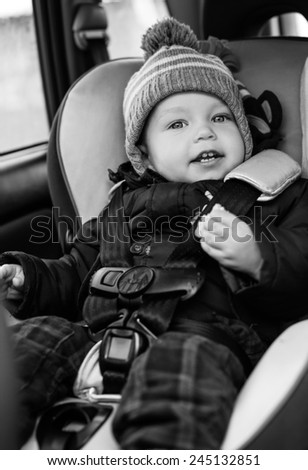 happy toddler boy sitting in the car seat ( black and white )