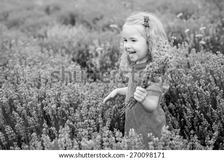 happy little girl in a field holding a bouquet of lavender ( black and white )