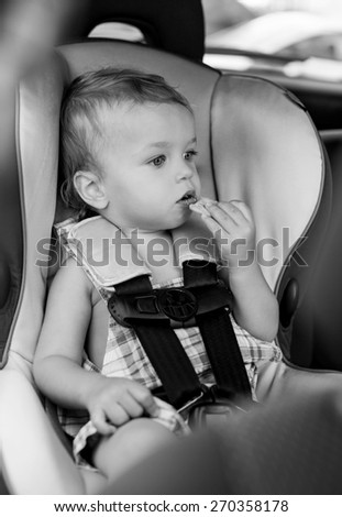 Happy Toddler boy in the car eating cookies  ( black and white )