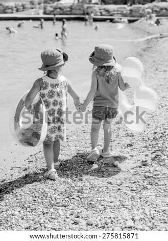 two friends with rings walking hand in hand on the summer beach ( black and white )