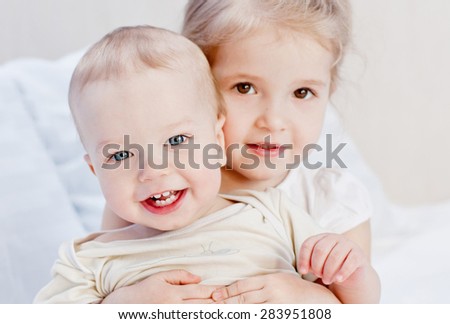 happy little sister hugging her brother on a white background