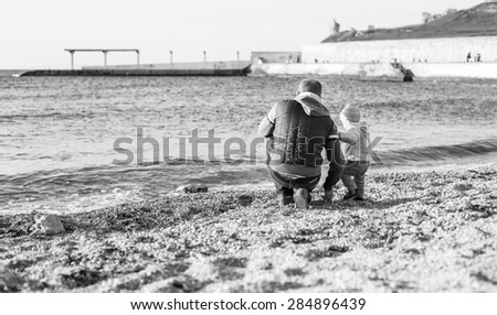 Dad and toddler son playing on the beach ( black and white )