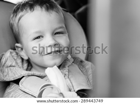 Happy Toddler boy eating a banana in the car  ( black and white )