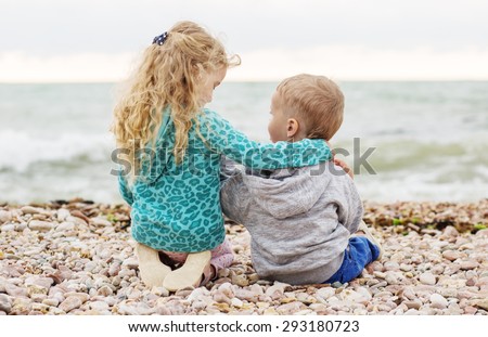 cute little brother and sister playing on the beach