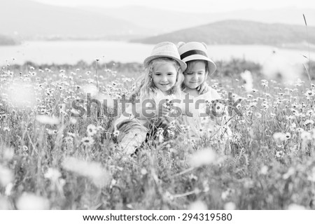 Two cute little girls hugging in the chamomile field  ( black and white )