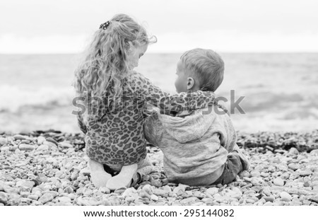 cute little brother and sister playing on the beach (  black and white )