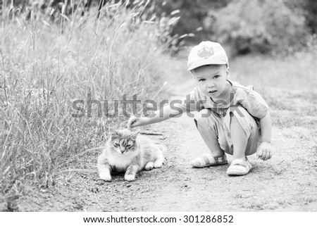 Toddler boy with a cat in nature  ( black and white )