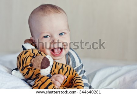 Happy baby in bed with a favorite toy