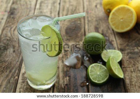 Fresh drink with lime and ice on wooden table